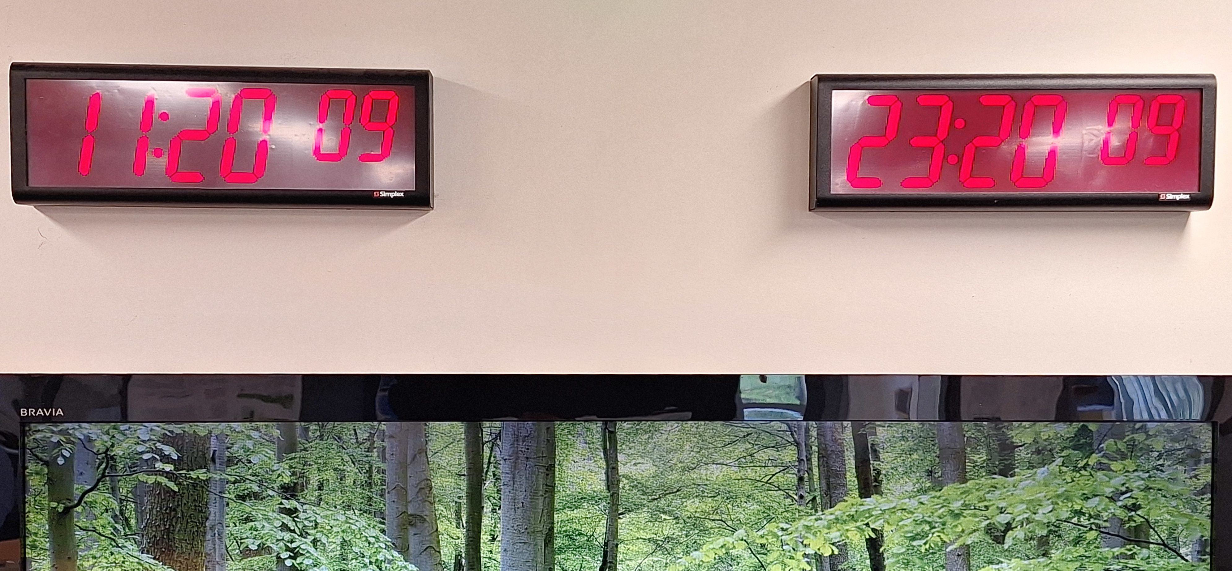 Clocks on the wall in the GeoNet staff response area at GNS Science. The clock on the left shows a local time of 11:20:09 AM NZST, and the clock on the right shows the UTC time of 23:20:09Z, the previous day.