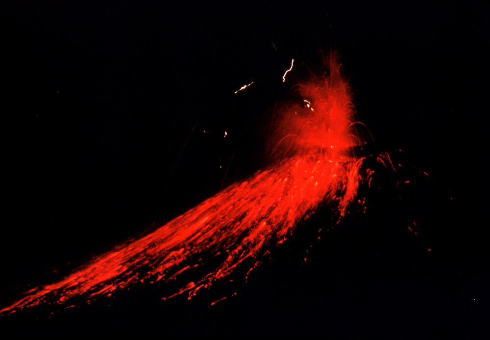 Nighttime time-lapse image of an explosive eruption (1974). You can see glowing blocks arching out of the vent, and lightning in the ash cloud.